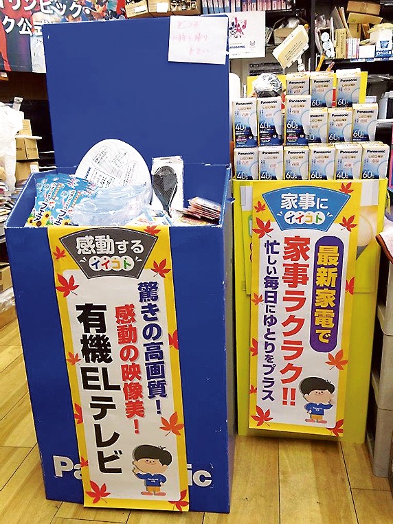 LEDコーナーの横で、粗品を来店客に贈呈