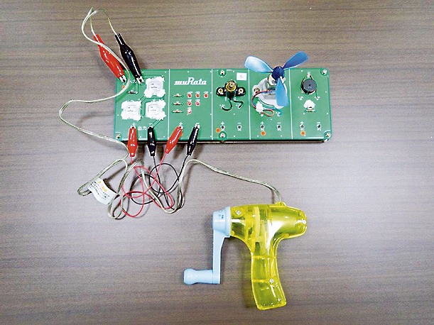 出前授業「電気エネルギーを考えよう」の教材。村田製作所の電気二重層キャパシタを実装した基板（上）と手回し発電機（下）