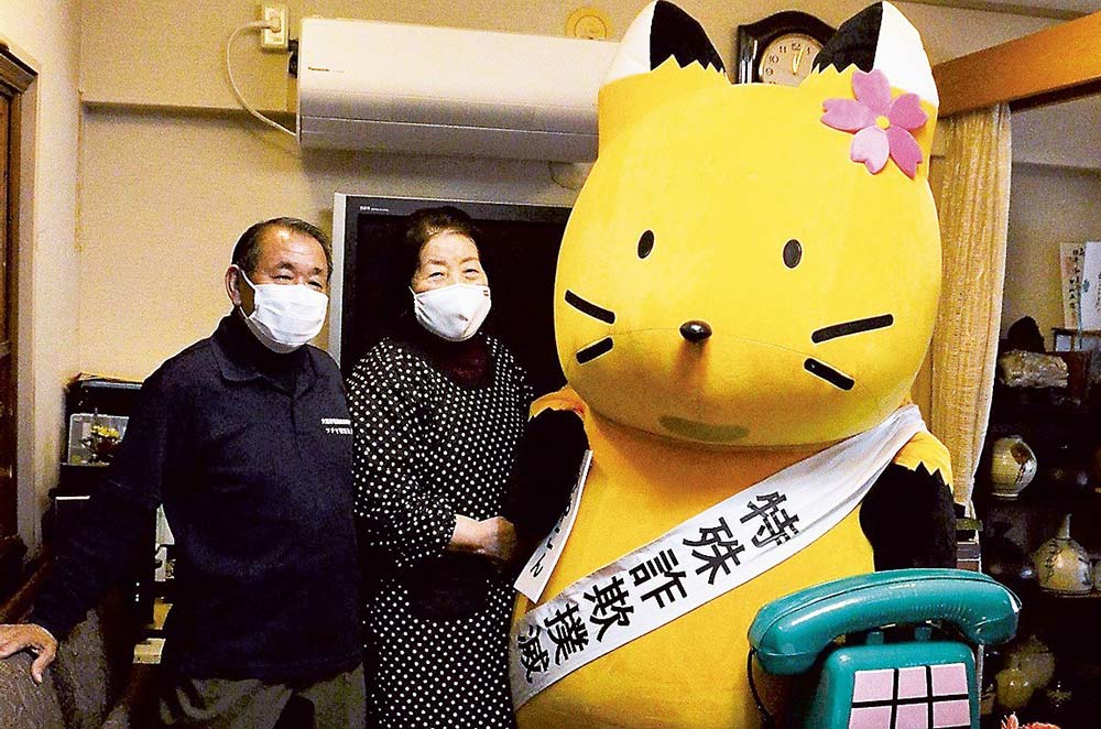 「これで安心」と喜ぶ住民と都島警察署特殊詐欺撲滅キャラクタ「みやこん」とで記念撮影