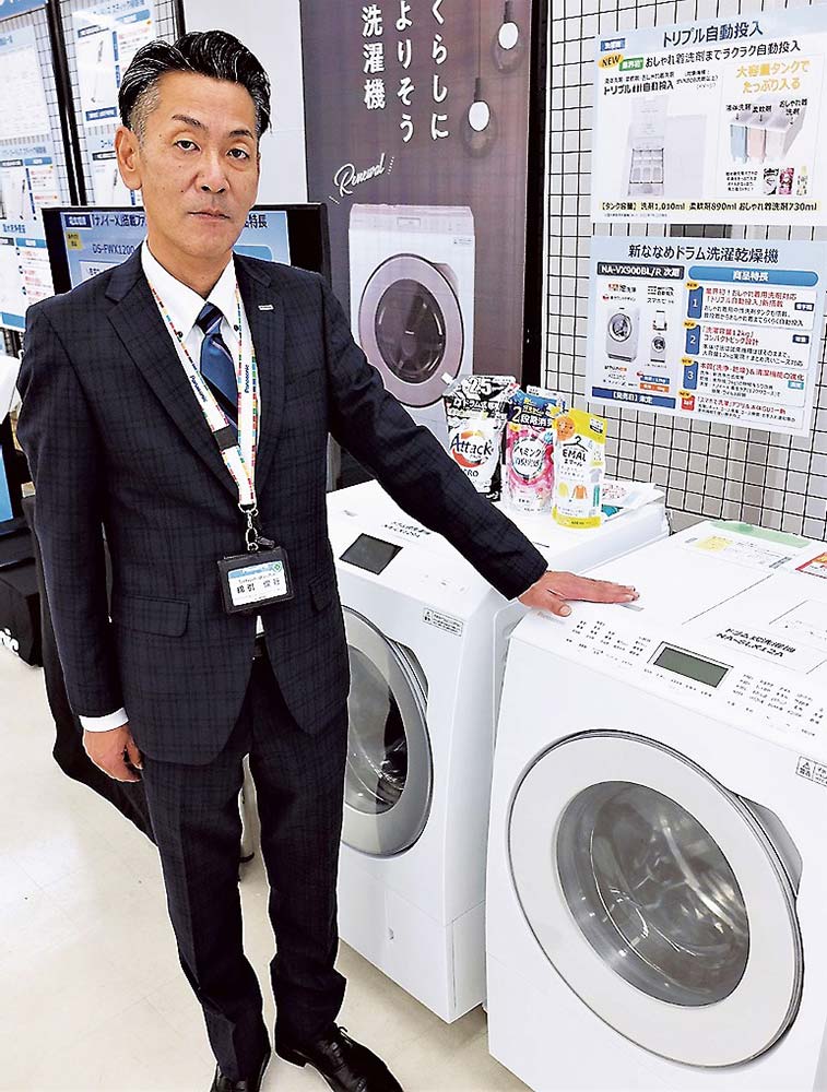 商品の横に立つ綿引支社長