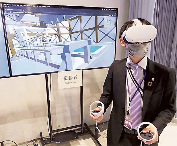 VR対応ゴーグルを装着し、メタバースを活用した原子力発電所の点検作業について説明する担当者＝東京都国分寺市