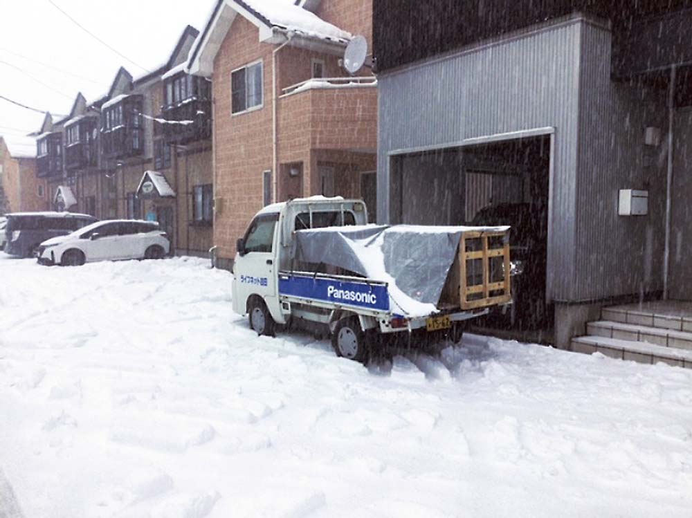 降りしきる雪の中でエコキュートの交換作業が行われた（提供写真）