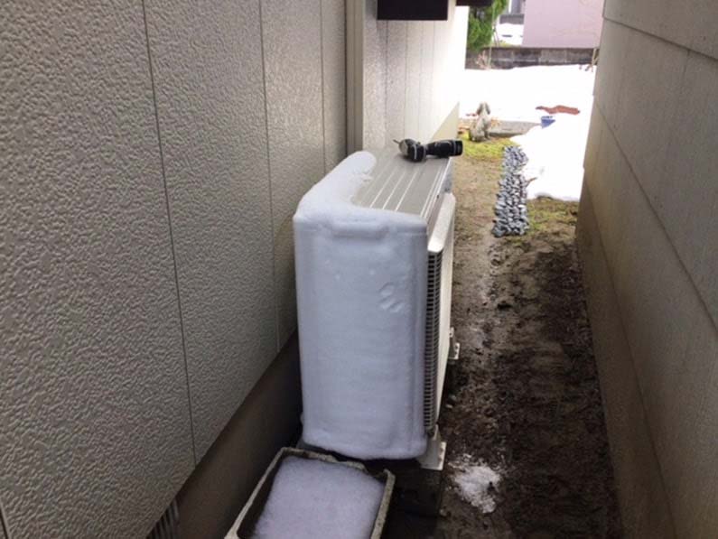 建物と建物の隙間に設置されている、霜に覆われた室外機（提供写真）