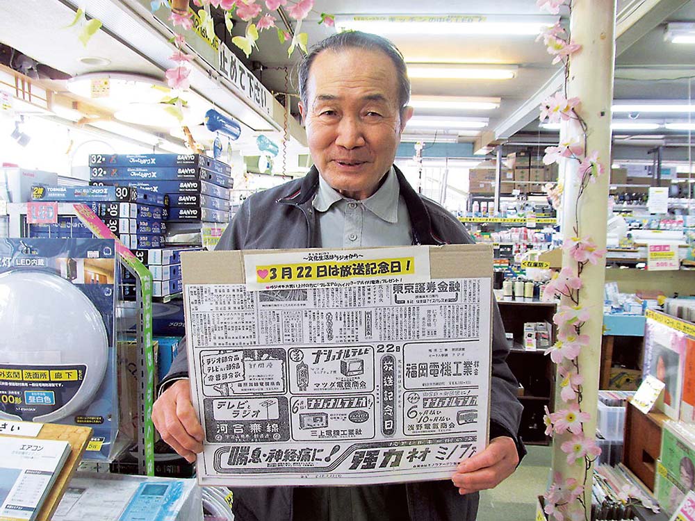 70年前の放送記念日特集の同店広告を見せる松田社長