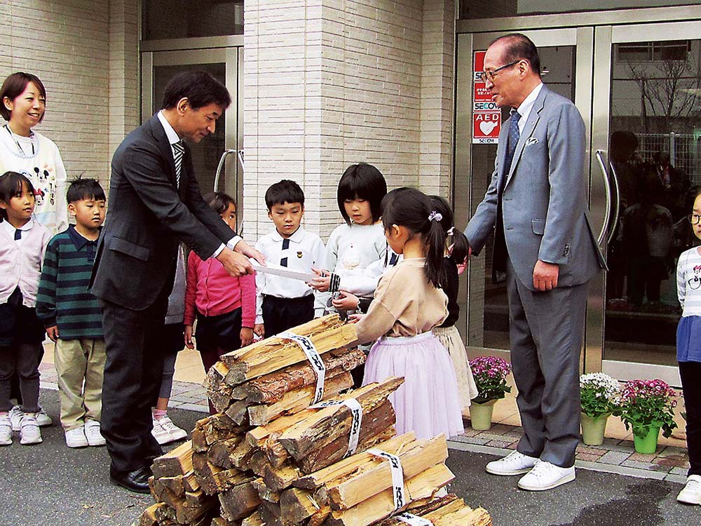 まきを寄贈する今瀬部長（右が前川町長）