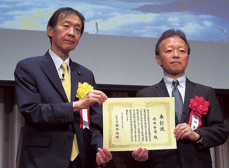 総務大臣賞を受賞した西田氏（右）と渡辺総務副大臣＝17日、東京都新宿区の京王プラザホテル