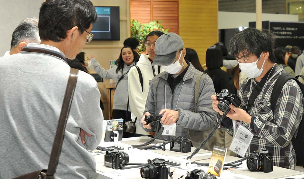 ミラーレスカメラを手に取る来場者（ニコンブース）