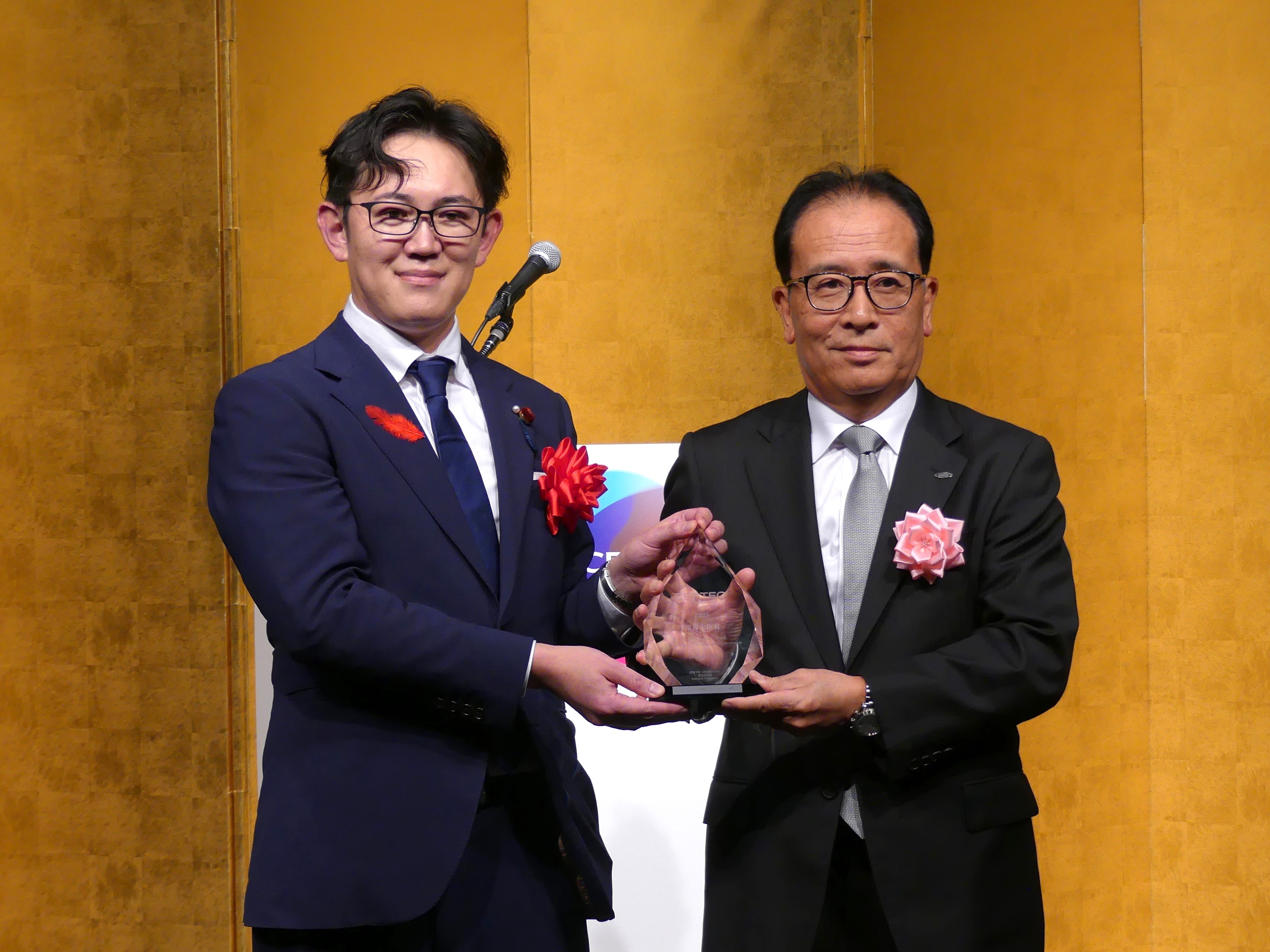 「総務大臣賞」を受賞したシャープの沖津雅浩社長執行役員CEO（右）と川崎総務政務官