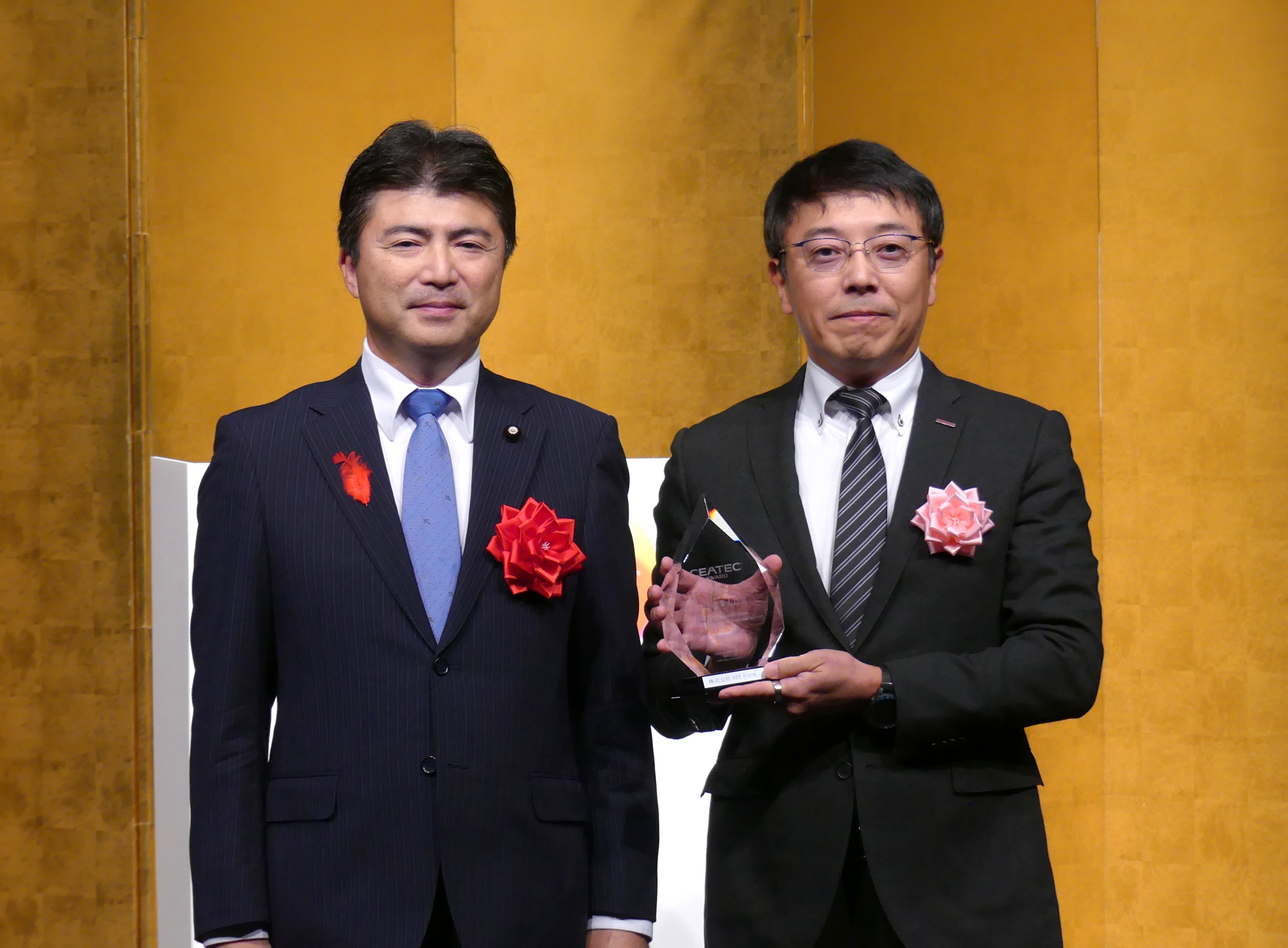 「経済産業大臣賞」を受賞したNTTドコモの佐藤隆明副社長（右）と古賀経産副大臣