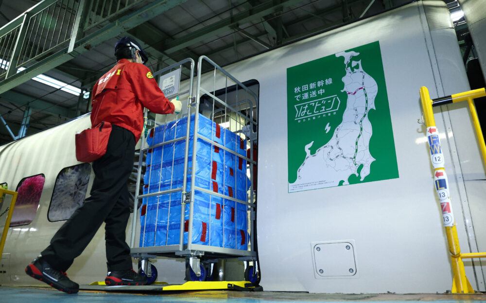 荷物専用新幹線から荷物を運び出す作業員＝23日午後、東京都北区