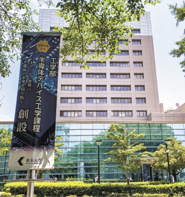 シンポジウムが開催された熊本大学の工学部百周年記念館。近くには、2024年に工学部に新設された「半導体デバイス工学課程」の垂れ幕が掲げられていた