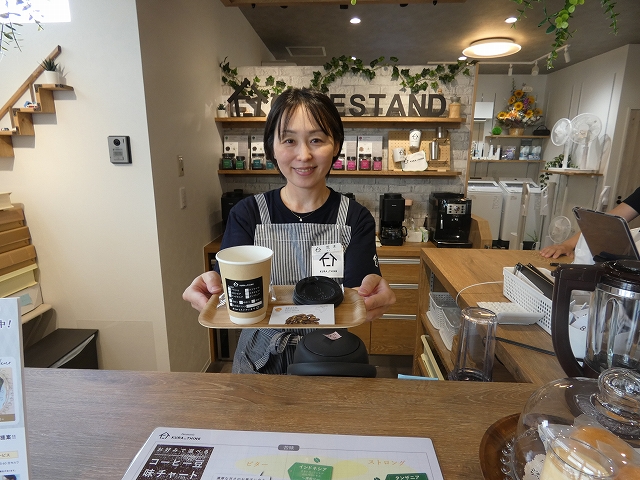 カフェスタンドでコーヒーと焼き菓子を手にする荒木博子店長。スペシャルティーコーヒーを提供する
