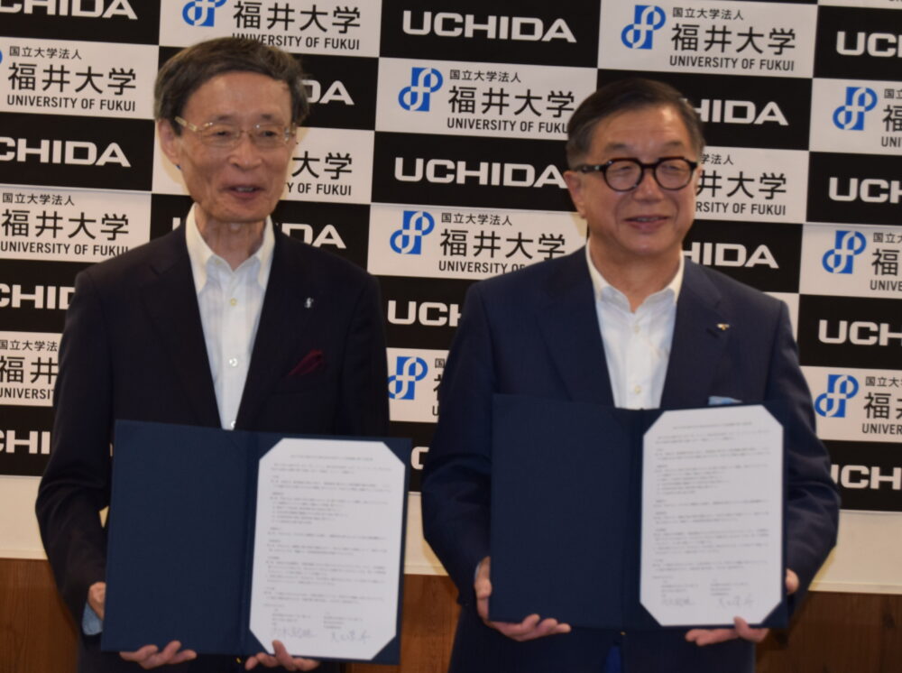 包括連携協定書を手にする福井大学の内木宏延学長（左）と内田洋行の大久保社長