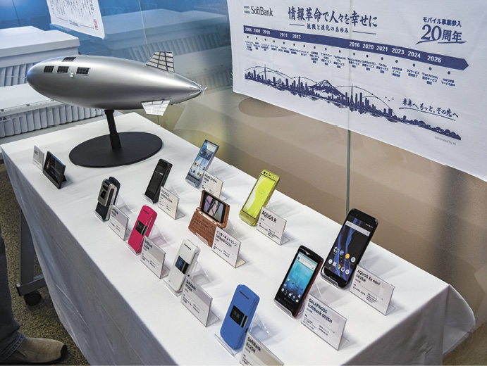記者発表の会場には、歴代のスマホやHAPS模型など20年の歴史を物語る製品群が並んだ