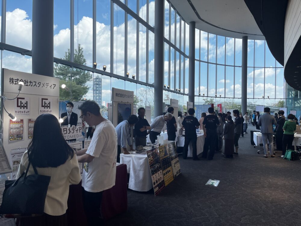ガラス張りのホワイエに設けられたブース展示会場。来場者が出展企業と交流した